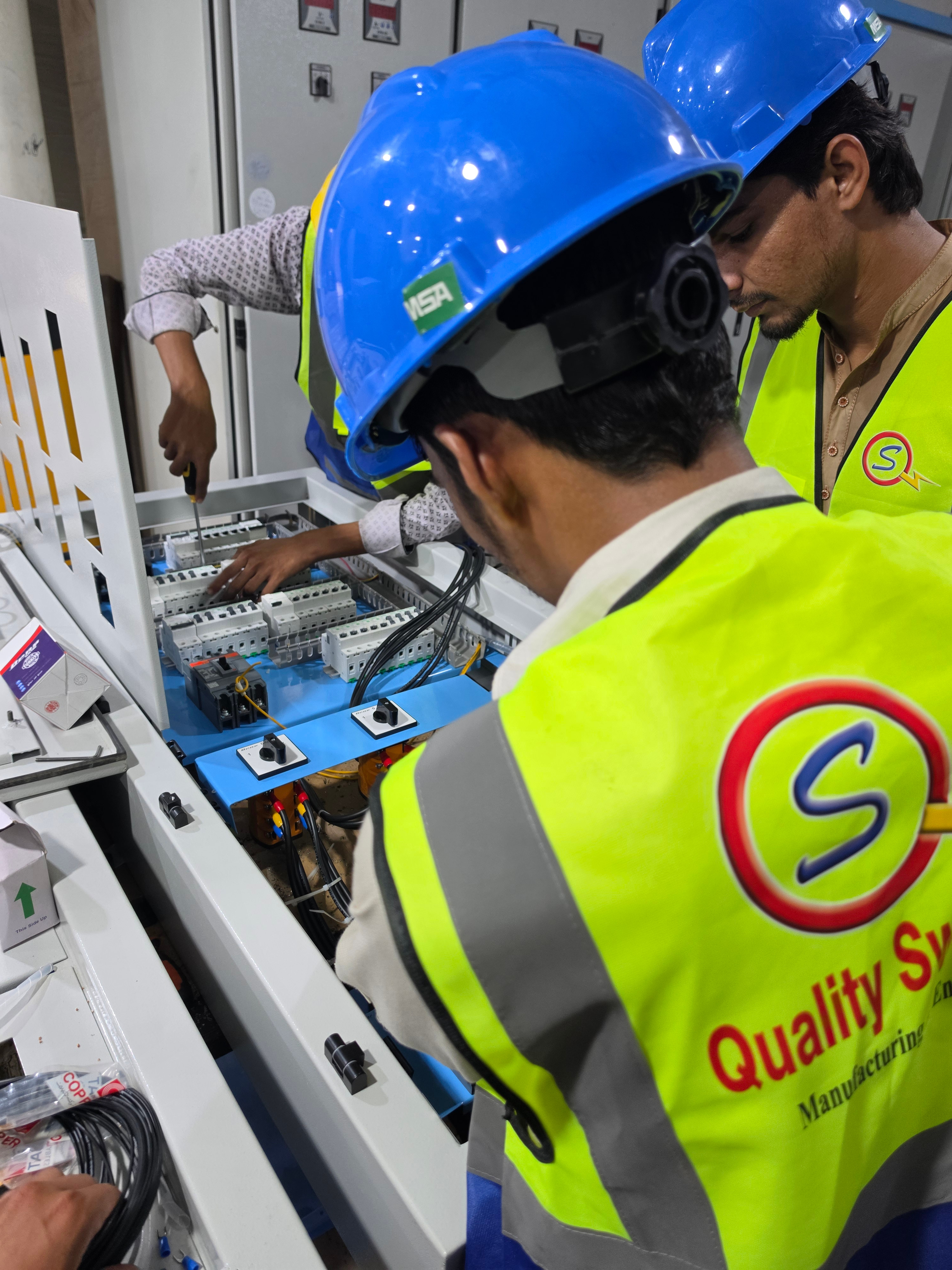 Technicians assembling a control panel on the Quality Switchgears shop floor.